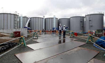 Workers stand near storage tanks for radioactive water at tsunami-crippled Fukushima Daiichi nuclear power plant in Okuma town, Fukushima prefecture, Japan