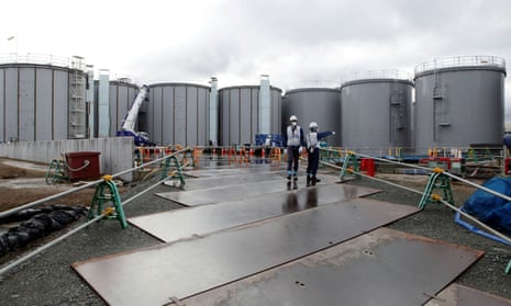 Workers stand near storage tanks for radioactive water at tsunami-crippled Fukushima Daiichi nuclear power plant in Okuma town, Fukushima prefecture, Japan 