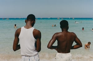 Two men with their backs to the camera with the sea in front of them