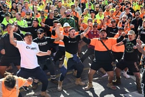 Crowd of people in high-vis vests, some with raised fists