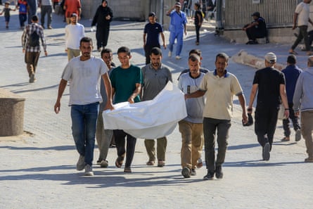 Relatives of people killed while waiting to access aid in Rafah transport a body from Nasser hospital for burial in Khan Younis.