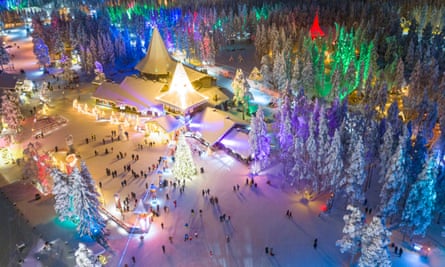 An aerial view of the Santa Claus village in Rovaniemi, Finland, with Christmas lights and snow.