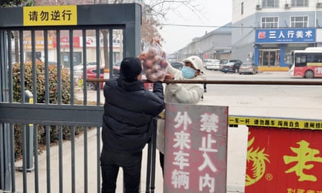 person hands food to another over a fence in Shanghai, which is under covid lockdown