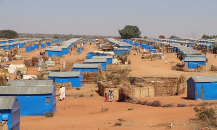 Lines of bright blue structures on red sandy land with only a few trees visible.