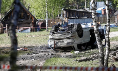 A damaged white Audi Q7 car lies overturned on a track next to a wood after an explosion that wounded Russian nationalist writer Zakhar Prilepin on 6 May.