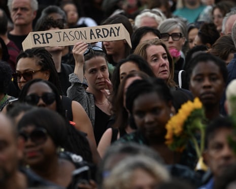 Mourners gather at a memorial for academic Jason Arday, one holding an "RIP" sign