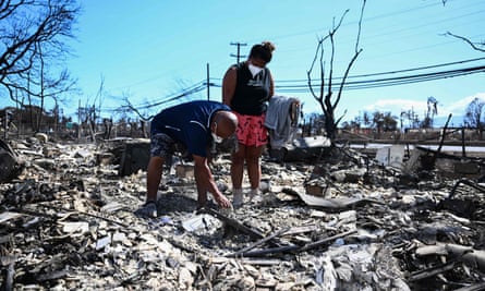 Two people look through the ashes of their family’s home in Lahaina after the wildfire