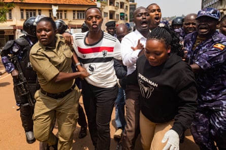 A group of shouting men are lead away by polie officers