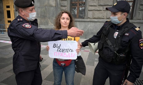 Police officers detain a journalist who holds a placard reading ‘You are afraid of the truth'
