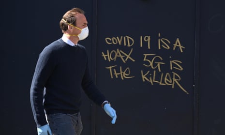 A man in a mask passes 5G conspiracy graffiti in London in April 2020. 