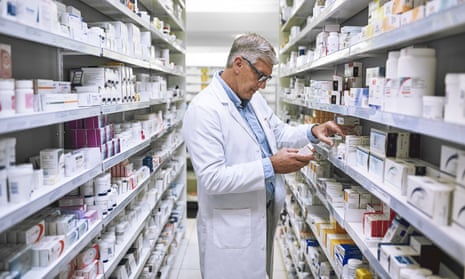 Pharmacist looking at medication among shelves of