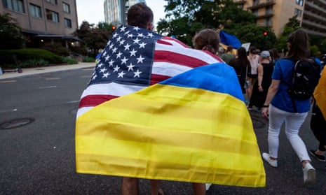 A couple wears a flag that combines the American and Ukrainian flags during a march celebrating Ukraine’s Independence Day in Washington in August.