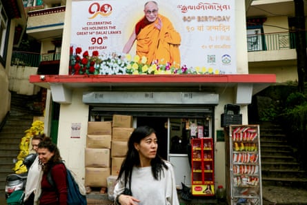 Women walk past a banner portraying the Tibetan spiritual leader Dalai Lama