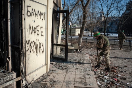 Ukrainian service member checks the damage of a building. The inscription on the building reads ‘Bakhmut loves Ukraine’.
