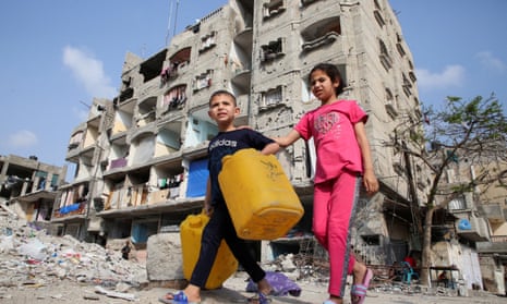 Palestinian children walk past a house damaged in an Israeli strike.