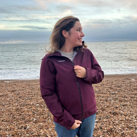 Writer testing the women’s Mammut Ducan waterproof jacket while walking on a shingle beach on a bright day.