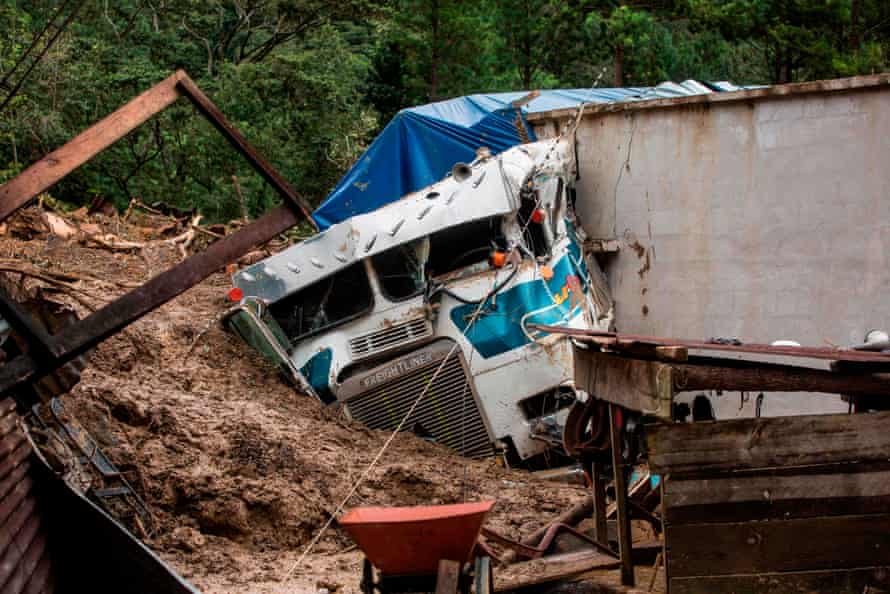 A truck is covered by mud at the side of a mudslide in the village of Queja, Guatemala.