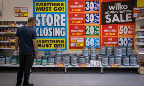 a man peruses goods in Wilko with a big sign saying 'closing down sale - everything must go'