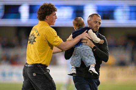Security officials holding the toddler and carrying them off the field.