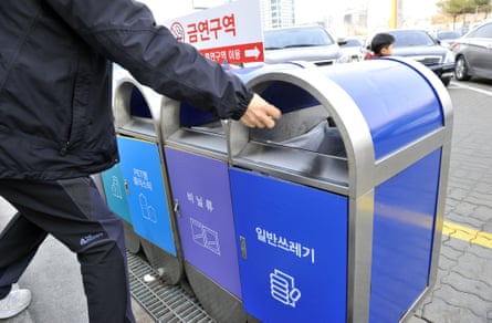 A person throws garbage into separated waste bins to recycle waste materials at a rest stop of an expressway in southern Seoul.