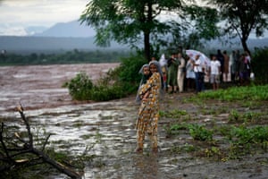 A girl carries a baby while waiting in a flooded rural area