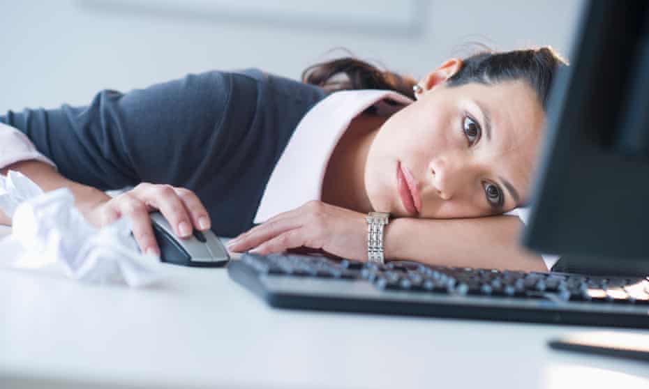 Businesswoman in front of computer, slumped on the desk looking tired.