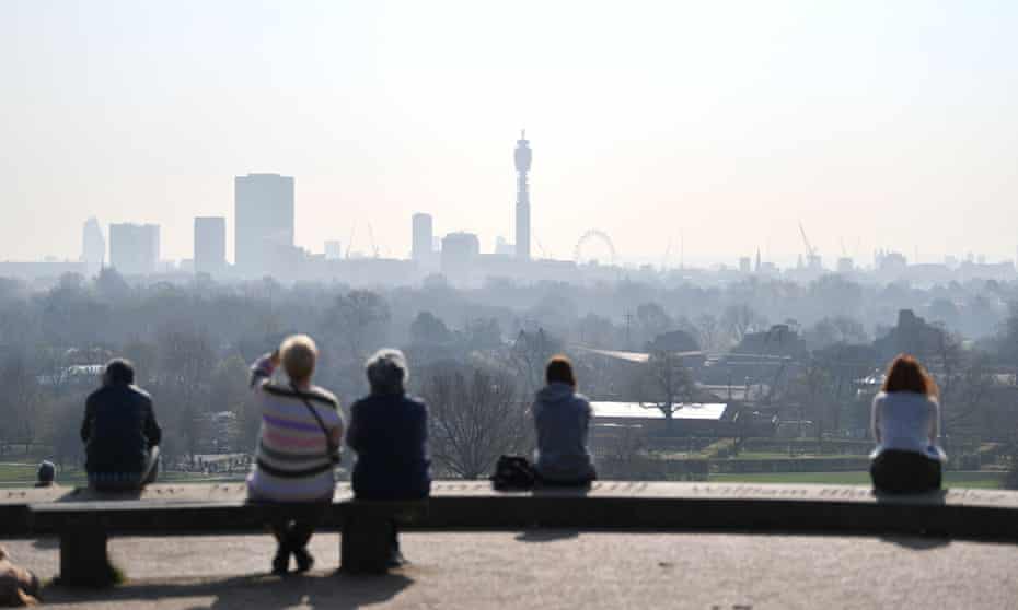 People at Primrose Hill with high air pollution visible over London. 
