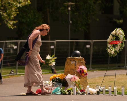 A woman places flowers at a memorial