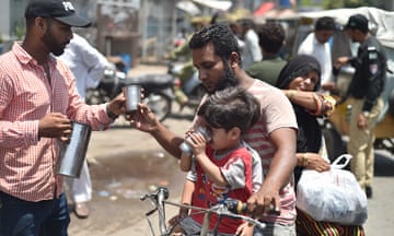 A Pakistani security official offers cold drinks to people in Karachi.