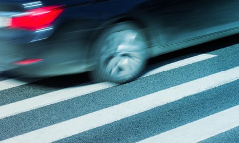 Horizontal side view of a black car with motion blur speeding over a pedestrian crossing