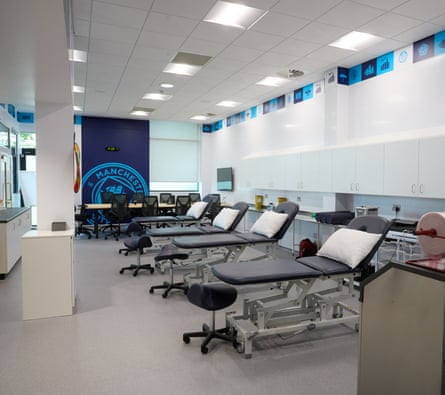 Treatment tables lined up in a room with the Manchester City logo in the background