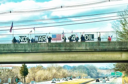 people hold signs in protest while standing on freeway overpass