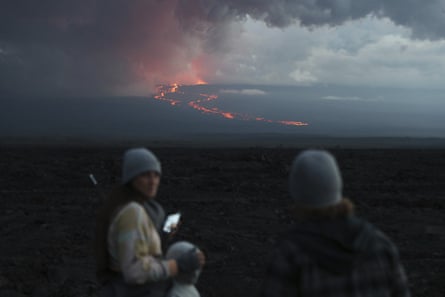 Spectators watch the lava flow down the mountain from the Mauna Loa’s eruption.