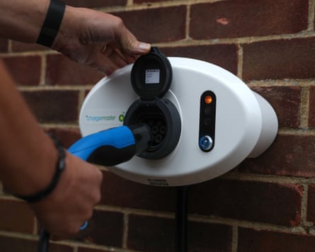 A person places an electric charging cable into a BP Chargemaster electric vehicle charging point