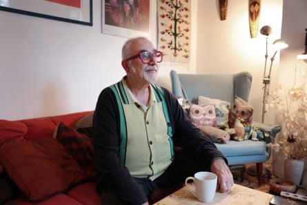 A man sits on a sofa with a cup of tea