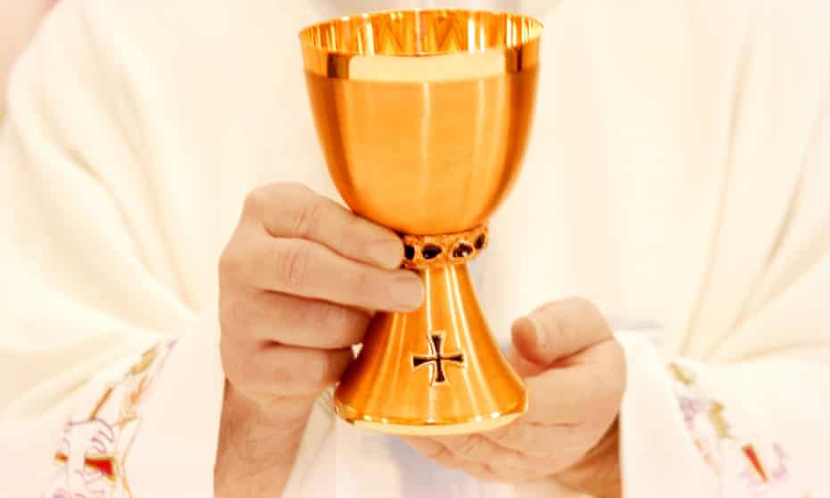 Priest holds a communion cup.