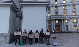A group of people hold signs at the front of the Ukrainian foreign ministry during a protest calling for the European Union to impose additional sanctions against Russia on 21 February in Kyiv, Ukraine.