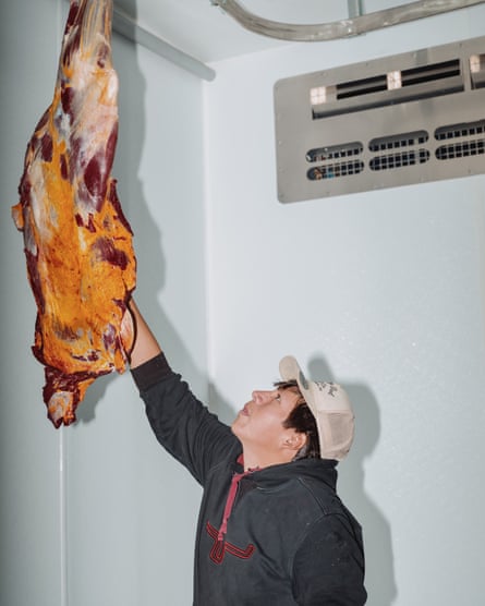 A man lifting a bison shoulder in an industrial setting.