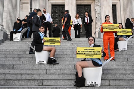People sit on toilets arranged at intervals on the entrance steps of Argentina’s National Congress holding signs saying ‘Senators, do not defecate in the water. The glacier law is untouchable’ in Spanish.