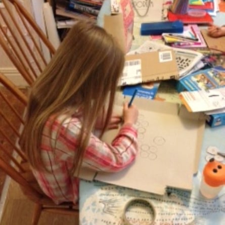 A child (face unseen) draws at the kitchen table