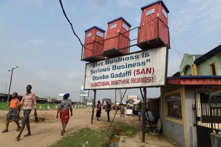 People walk past mobile toilets for sale displayed along the road with a placard reading “shit business is serious business” at Kara-Isheri in Ogun State, southwest Nigeria.