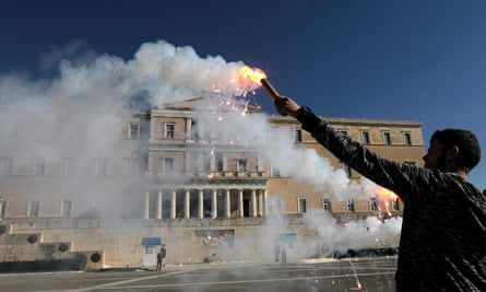 A student holds a flare in front of the parliament during an anti-austerity protest in Athens, Greece.