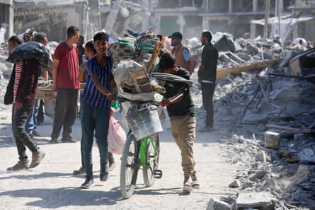 Two boys push a bicycle loaded with possessions.