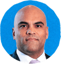 man in suit looks ahead with soft smile against blue background