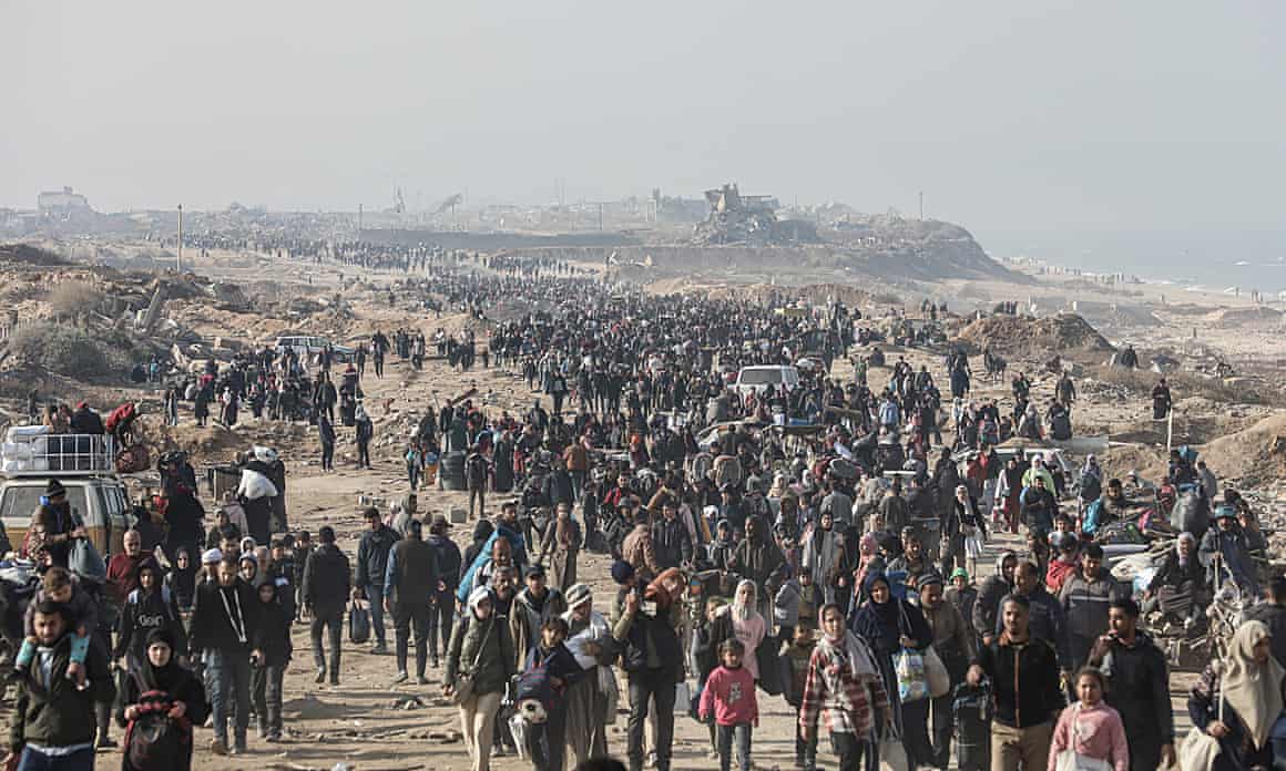 Displaced Palestinians walk on a road to return to their homes in northern Gaza