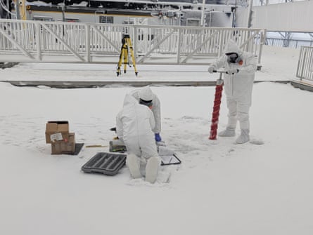 People wearing hazmat suits work on an ice-covered control pool.