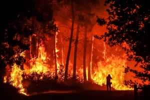 A silhouette is seen in front of flames at a wildfire near Belin-Beliet, south-western France on 11 August