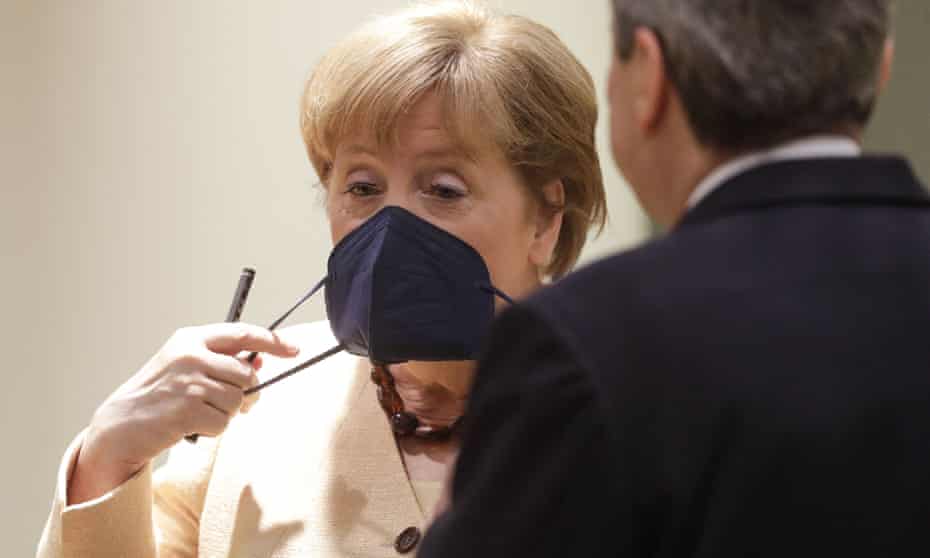 Angela Merkel adjusts her mask on the second day of the EU summit