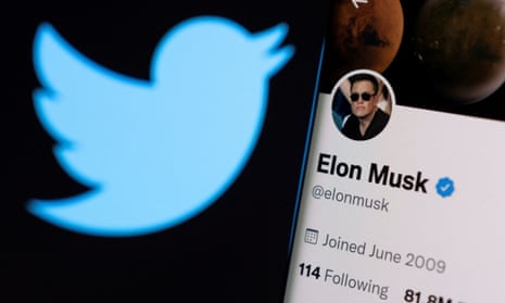 Elon Musk's Twitter account is seen on a smartphone in front of the Twitter logo.