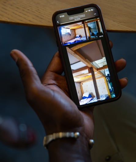 A man’s hand holds a phone showing images from inside a dormitory.